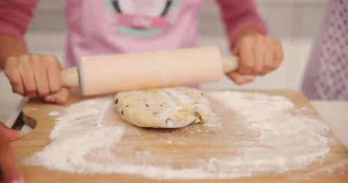 Child Rolling Dough with Rolling Pin on Wood Board
