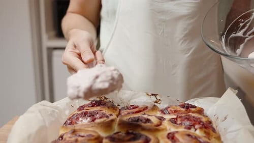 Spreading Creamy Frosting over Warm Rolls, Adding the Finishing Touch.