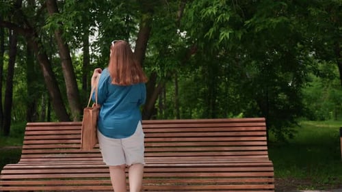 Mujer sentada en un banco de madera quitando objetos de la bolsa en el parque