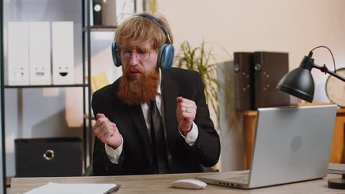 Young Business Man Working on Laptop at Home Office Wearing Earphones Listening Favorite Disco Music