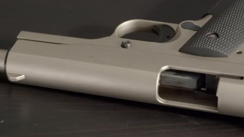 Panning back and forth over barrel of open and empty pistol.