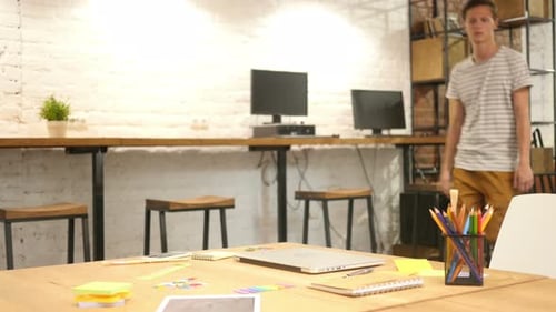 Young Man Coming to Office and Opening Laptop