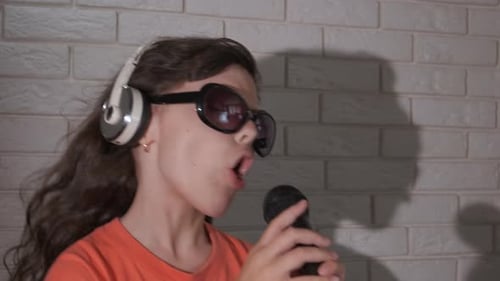 Child Sings into Microphone Wearing Headphones and Sunglasses