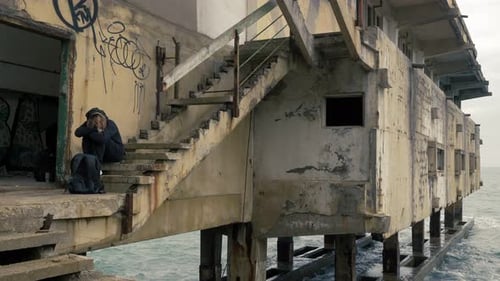 social issue - young homeless on the stairs of an old building by the sea