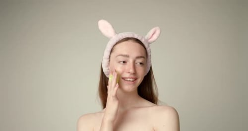 Woman Applies Skincare Lotion to Face with Sponge