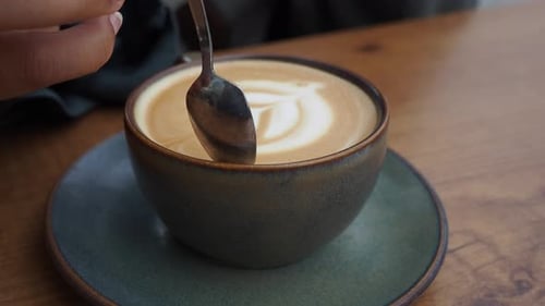 Coffee with Latte Art Being Stirred