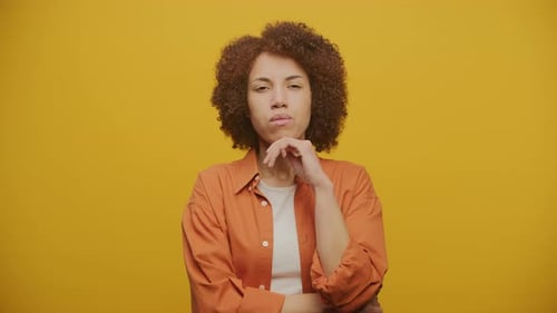 Contemplative Woman Posing in Front of Yellow Background