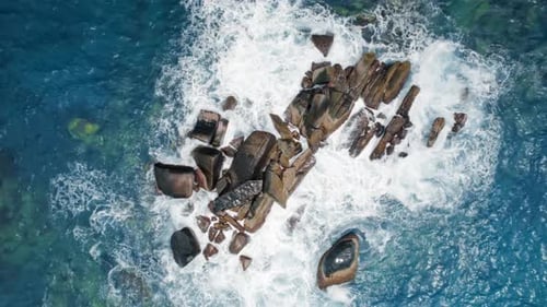 Aerial view of powerful ocean waves crashing on rocky coastline