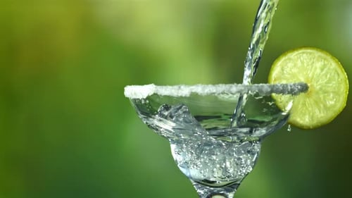Pouring Refreshing Drink into Margarita Glass with Lime