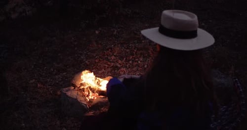 Rear View of a Young Adult Woman with Long Hair and Wearing a White Hat Against the Background of a
