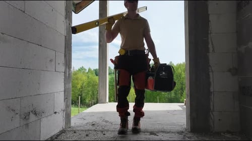 Construction Worker Carrying Tool in Front of Building