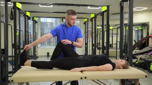 Man Stretching Woman's Leg at Physical Therapy Session