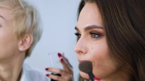 closeup view of model girl getting professional makeup by makeup artist at beauty salon