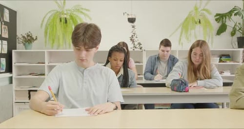 Focused Students Writing Essay Test Exam in School Class. High School - College Alumni