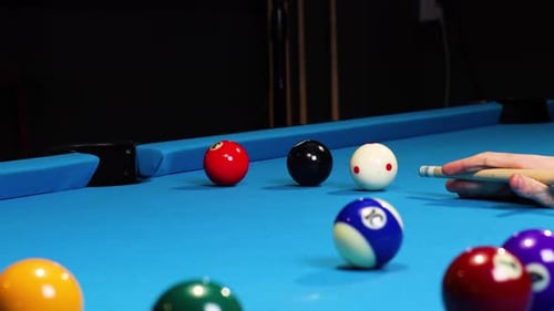 Playing a game of pool billiards hitting balls and white ball going into a pocket.