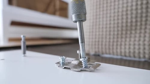 Slow motion close up of a screwdriver screwing in a screw in a wardrobe door latch