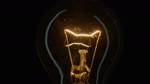 Incandescent Bulb Turns on and Off Flickers on Black Closeup Flashing Filament