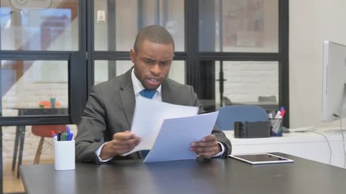 Man Looks Worried While Reading Papers in Office