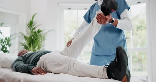 Medical Professional Assists Senior with Physical Therapy