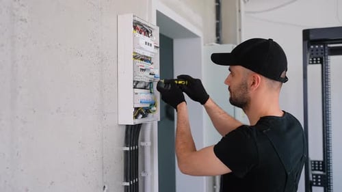 Technical Electrician Fixing the Cable Into the Terminal of a Circuit Breaker of a Electrical Panel