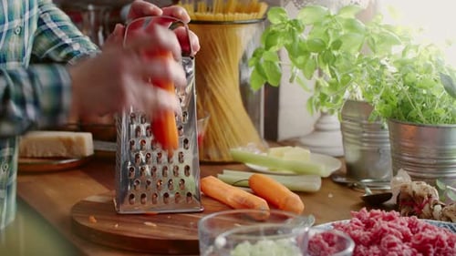 Person Grating a Fresh Carrot in a Bright Sunlit Kitchen