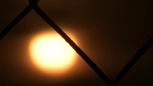 Silhouetted Fence Over Glowing Light at Sunrise