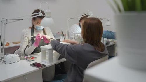 Nail Technician Files Client's Nails in Salon