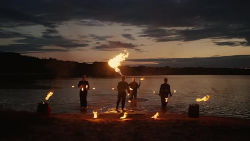 Group Of Professional Stunt Persons Working With Fire Artistic Fire Show On River Beach