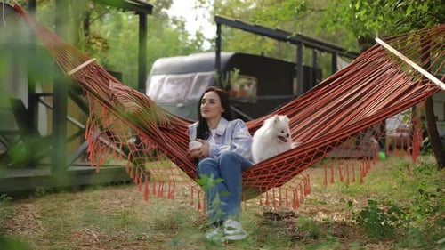 Woman Relaxing in Hammock with White Dog