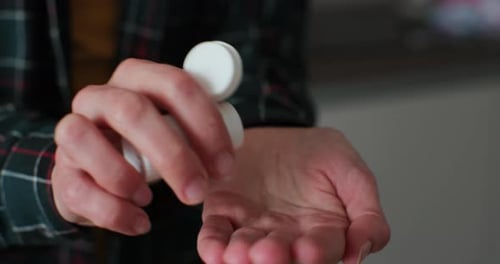 Pills Being Poured From White Bottle to Hand