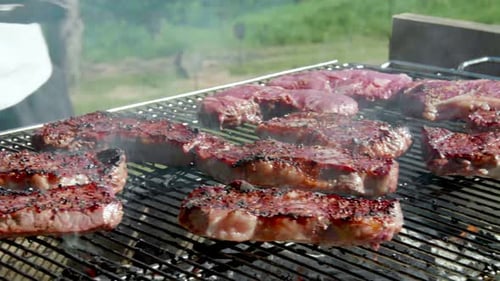 Beef steaks sizzle on the grill in slow motion tracking shot food presentation