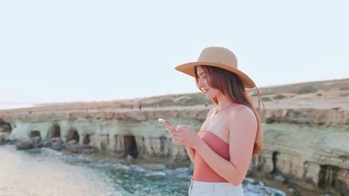 Woman with Phone Enjoying Ocean Sunset View