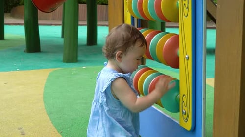 2 Jahre altes ukrainisch-koreanisches Süßes kleines Mädchen, das lernt und Spaß daran hat, bunte Scheiben zu drehen