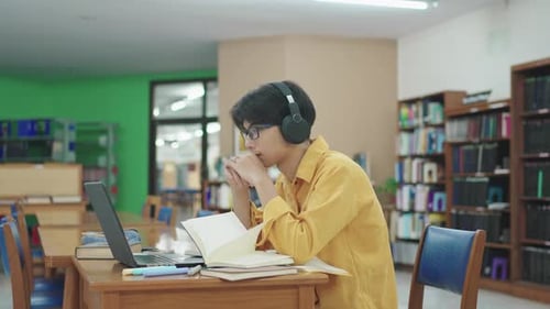 Student, thinking and man in library, laptop and typing with education, university and knowledge.