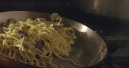 Super slow motion macro of a middle aged chef flipping spaghetti with a pan (close up)