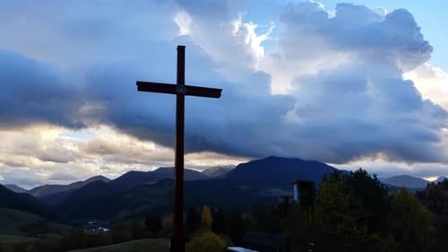 Christian Cross in Mountain Rural Landscape Clouds in Blue Sky at Dusk