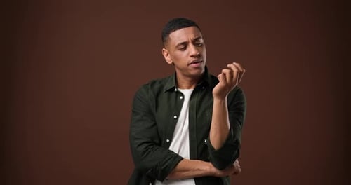 Nachdenklicher Afroamerikaner zählt auf seine Finger und steht über braunem Studiohintergrund