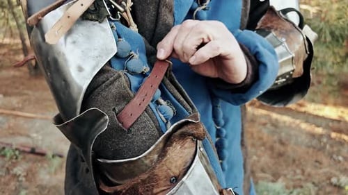 Mittelalterlicher Ritter zieht Kleidung und Rüstung an