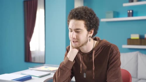 Young uni student is bored, confused and depressed by studying at home.