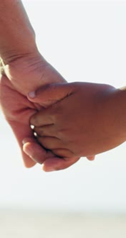 Adult and Child Holding Hands on Beach