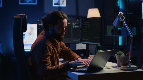 Computer Scientist Putting Headphones on While Developing Code on PC