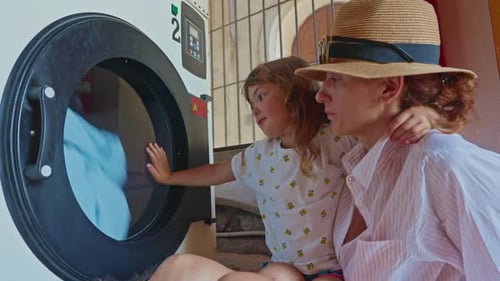 Mother and Child Watching Clothes Spin in Washer