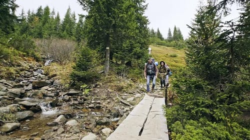 Group of Young People Crossing Mountain River