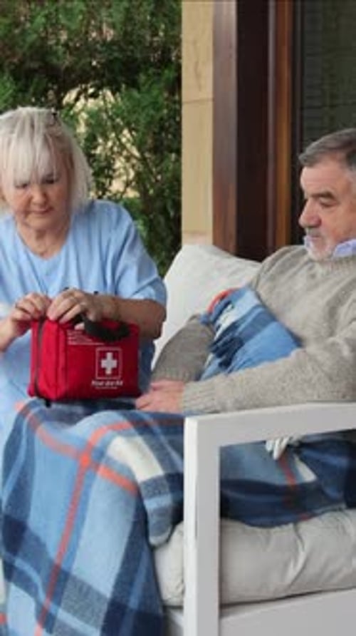 Woman Opens First Aid Kit for Man on Porch