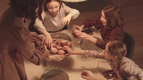 Family Enjoys Pastries at Dinner Table Indoors