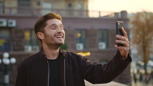 Smiling man video chats in city environment
