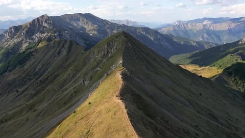 A Drone Flies Along a Picturesque Green Mountain Range Illuminated By the Setting Sun