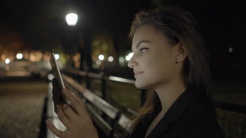 Young Woman Using Tablet Computer In The Park At Night