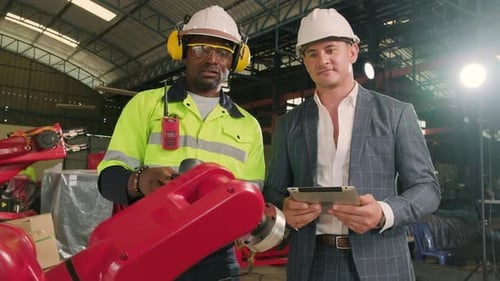 An engineer demonstrates robotic arm control to customer in industry factory.