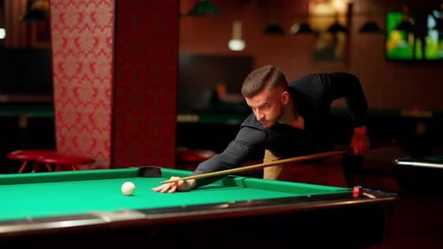 Young Adult Plays Billiards in Dimly Lit Bar